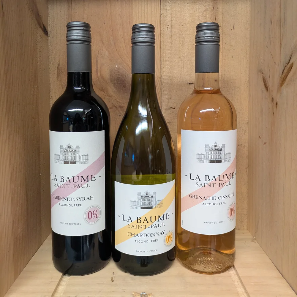 Drie flessen alcoholvrije wijn van La Baume Saint-Paul in een houten kist: een rode Cabernet-Syrah, een witte Chardonnay en een rose Grenache-Cinsault