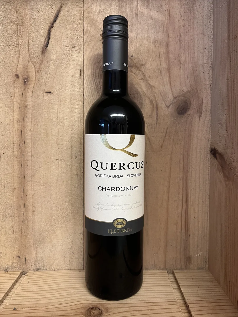 De fles Quercus Chardonnay 2025 uit Goriska Brda in Slovenie, staand in een houten kist